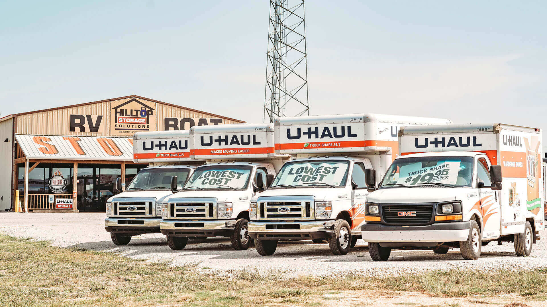 Hilltop Storage Solutions of Northlake is a rental supplier of U-Haul rental trucks and moving and storage supplies. Image of four U-Haul moving trucks lined up in front of the store.
